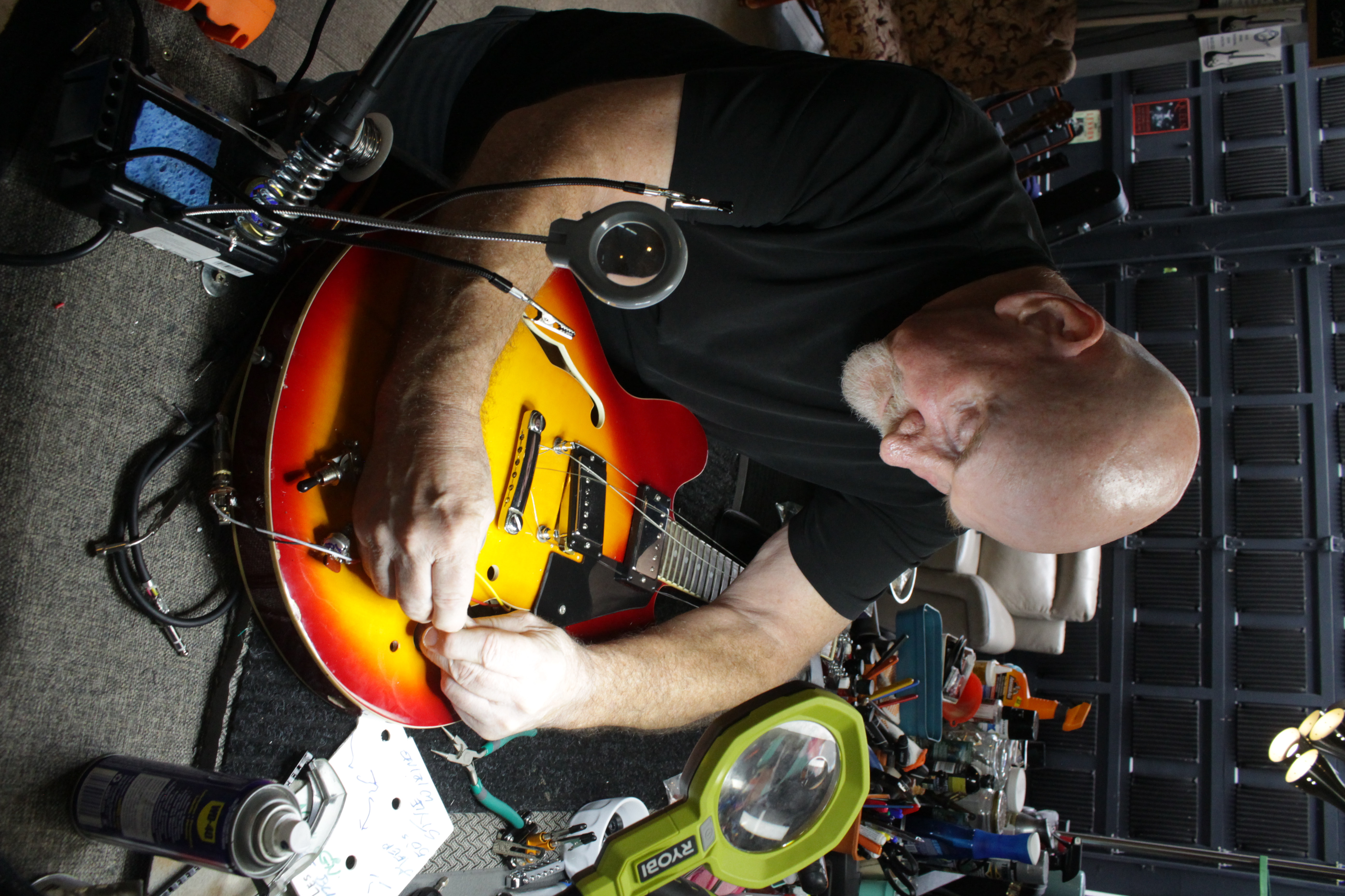 Overhead view of guitar repair technician working on instrument electronics