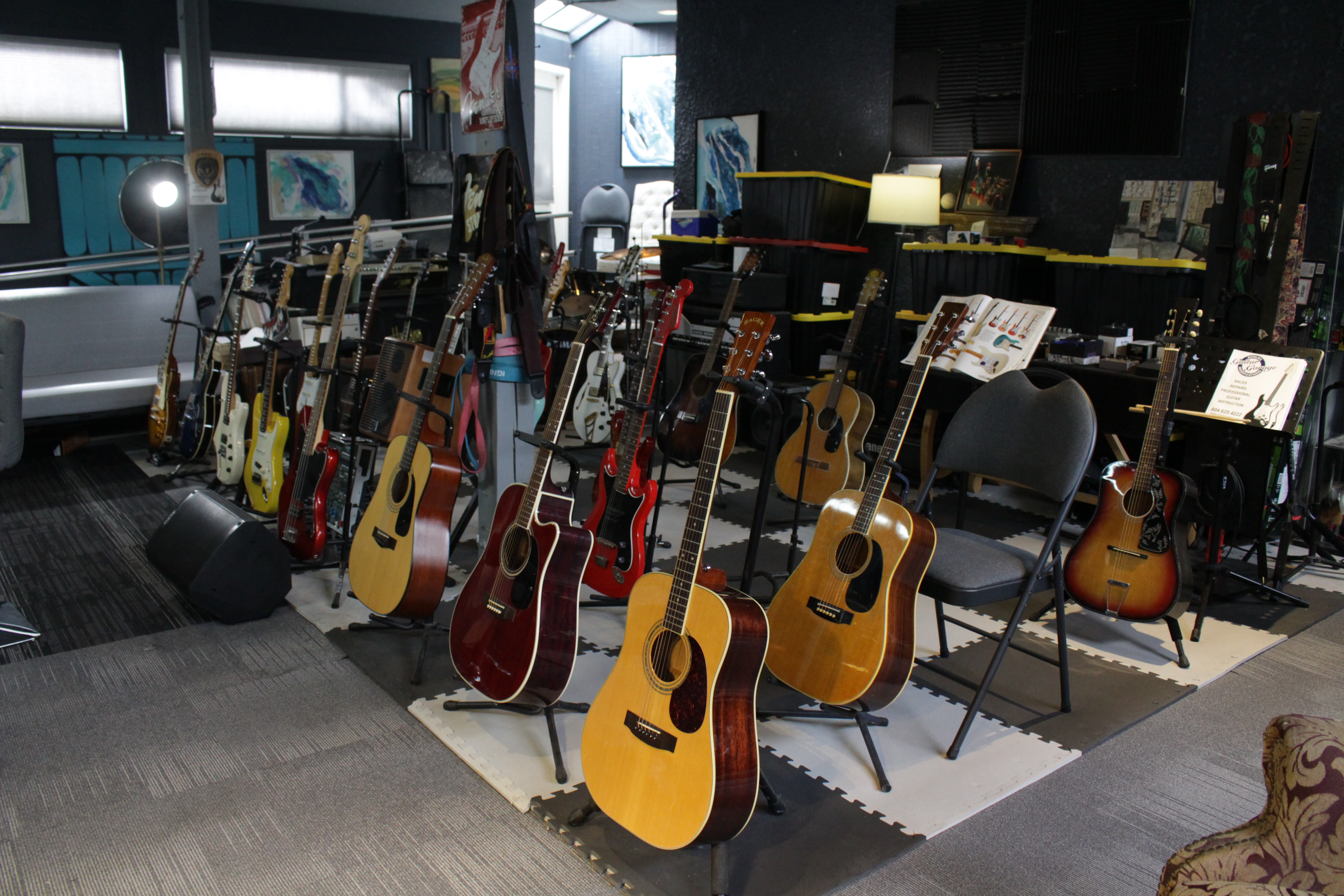 Multiple acoustic guitars on display stands in GuitarGarage showroom